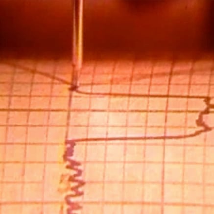 Needle recording vibrational activity on squared paper roll